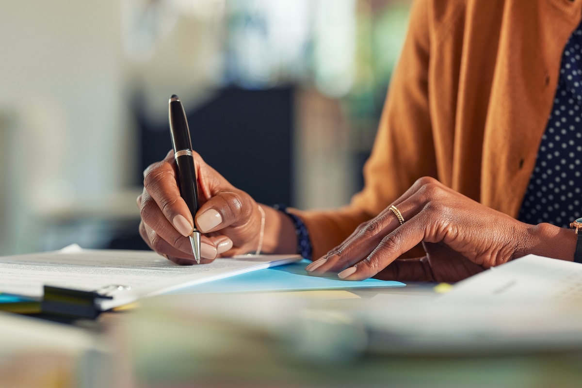 business woman hand writing on paper at desk
